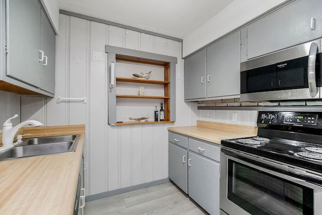 kitchen with electric stove, gray cabinets, light countertops, stainless steel microwave, and a sink