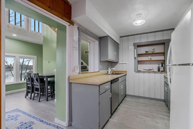 kitchen featuring dishwasher, a sink, gray cabinets, and freestanding refrigerator