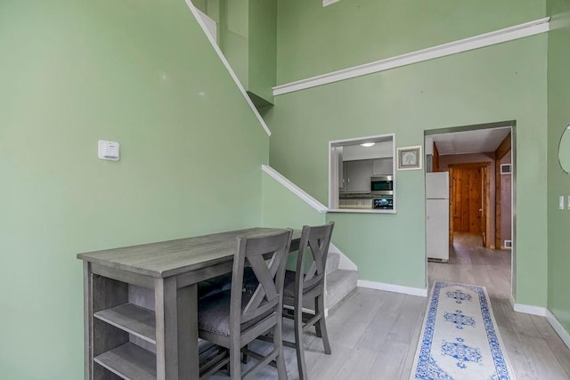 home office with a high ceiling, baseboards, and wood finished floors