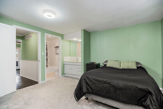 bedroom featuring ensuite bath, carpet, visible vents, and a sink