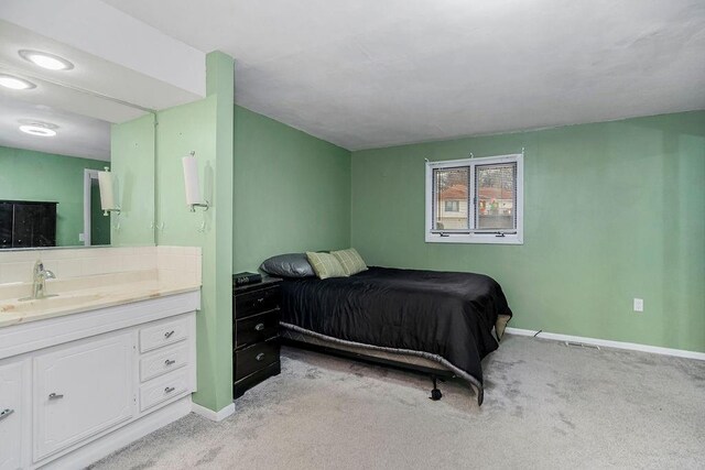 bedroom with light carpet, a sink, ensuite bath, and baseboards