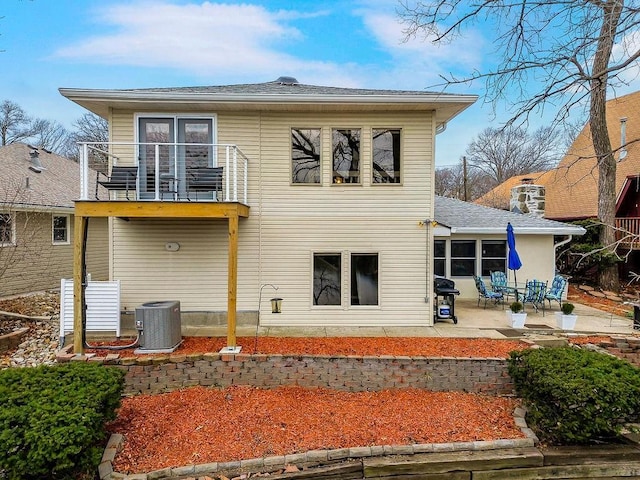 back of house featuring central air condition unit, a balcony, and a patio