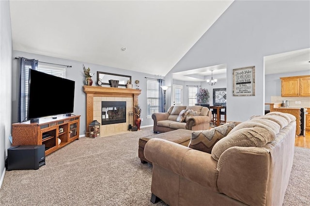 carpeted living room with a fireplace, baseboards, a chandelier, and high vaulted ceiling