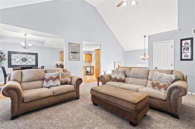 carpeted living room with ceiling fan with notable chandelier, high vaulted ceiling, and baseboards