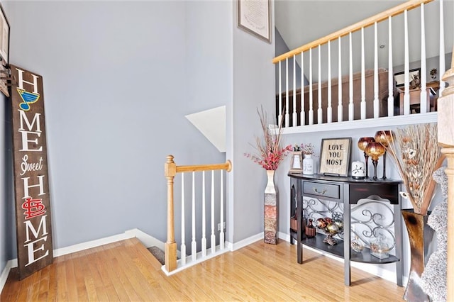 staircase featuring baseboards, wood finished floors, and a towering ceiling