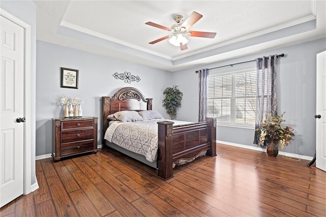 bedroom with a raised ceiling, baseboards, and dark wood-type flooring