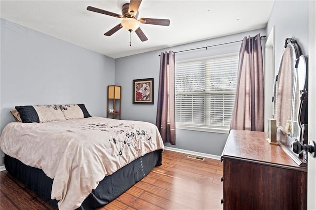 bedroom with visible vents, baseboards, a ceiling fan, and hardwood / wood-style flooring