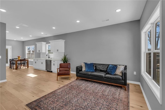 living area with recessed lighting, light wood-type flooring, and baseboards