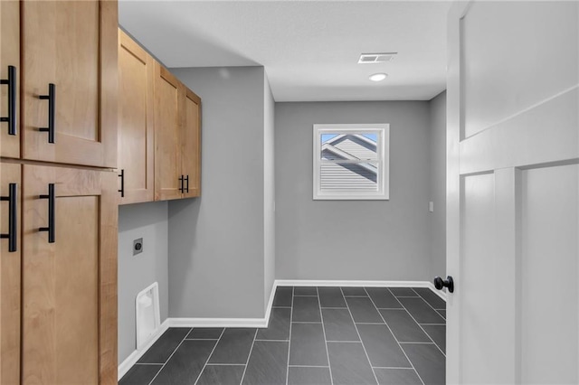 washroom featuring visible vents, baseboards, cabinet space, hookup for an electric dryer, and dark tile patterned flooring