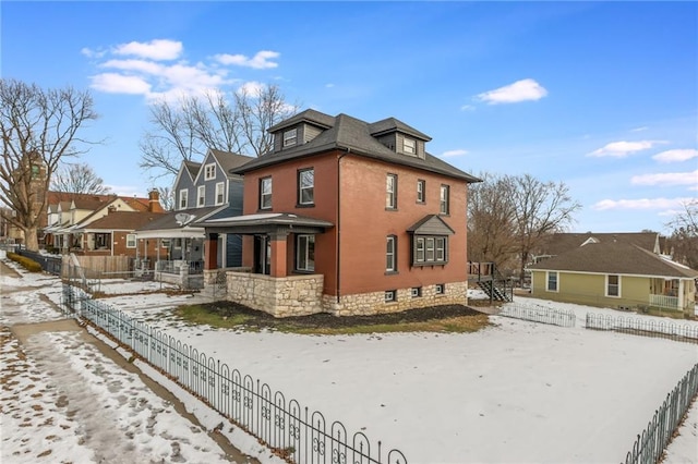 snow covered property with a residential view and fence