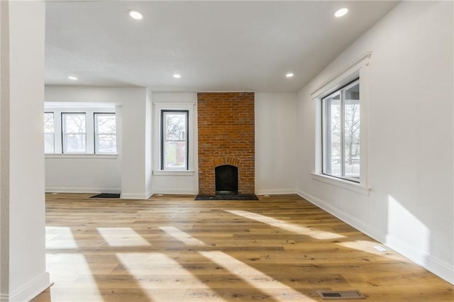 unfurnished living room featuring plenty of natural light, light wood-style flooring, and a fireplace