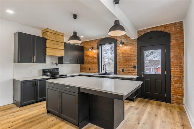 kitchen with light wood finished floors, light countertops, electric range, a sink, and brick wall