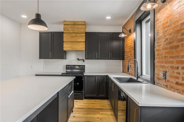 kitchen featuring light countertops, dark cabinetry, light wood-type flooring, black appliances, and a sink