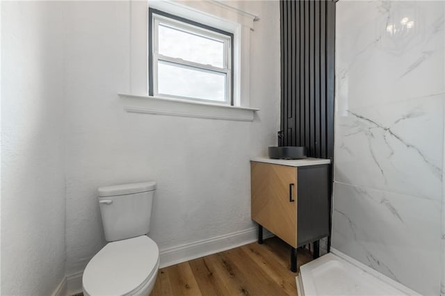 full bathroom featuring baseboards, toilet, wood finished floors, walk in shower, and vanity