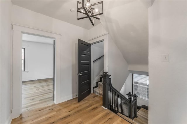 stairs with baseboards, a chandelier, and wood finished floors