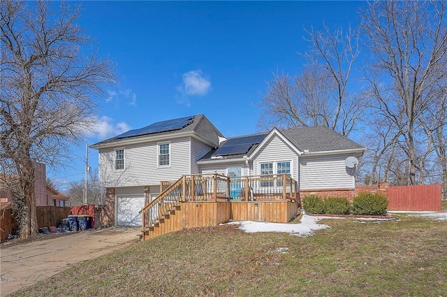 rear view of house featuring brick siding, a yard, roof mounted solar panels, fence, and a garage