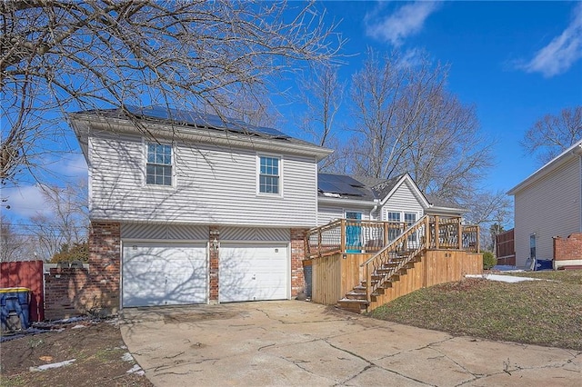 view of front facade featuring a garage, concrete driveway, stairway, roof mounted solar panels, and brick siding