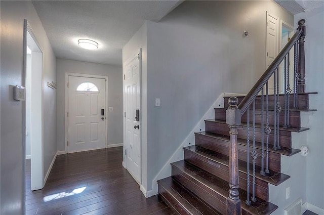 entryway with a textured ceiling, stairs, baseboards, and hardwood / wood-style floors