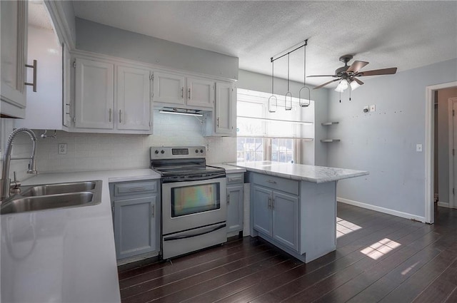 kitchen featuring electric stove, backsplash, a peninsula, light countertops, and a sink