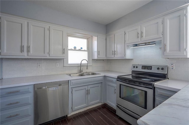 kitchen with dark wood-style flooring, stainless steel appliances, white cabinets, a sink, and exhaust hood