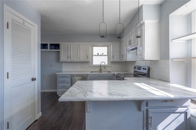 kitchen featuring dark wood-style floors, a peninsula, a sink, stainless steel appliances, and backsplash