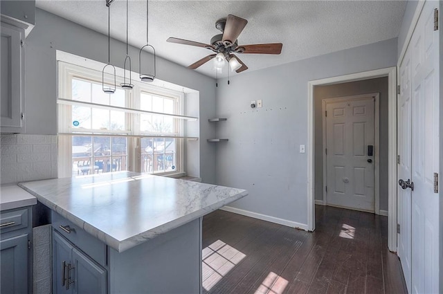 kitchen with tasteful backsplash, baseboards, dark wood-type flooring, a peninsula, and light countertops