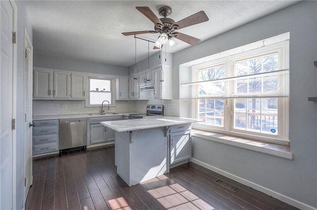 kitchen featuring light countertops, visible vents, appliances with stainless steel finishes, a sink, and a peninsula