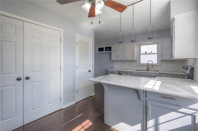 kitchen with a peninsula, range with electric cooktop, a sink, light stone countertops, and dark wood-style floors