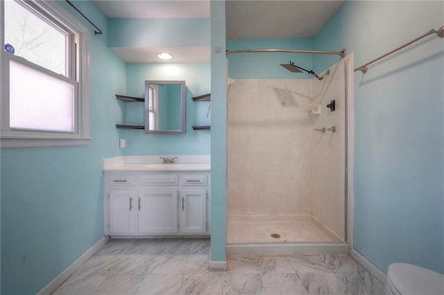 bathroom featuring marble finish floor, tiled shower, toilet, and baseboards