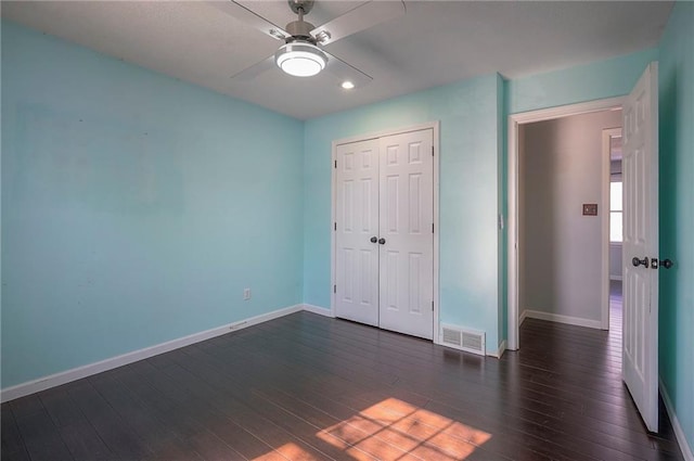 unfurnished bedroom with dark wood-style flooring, visible vents, and baseboards