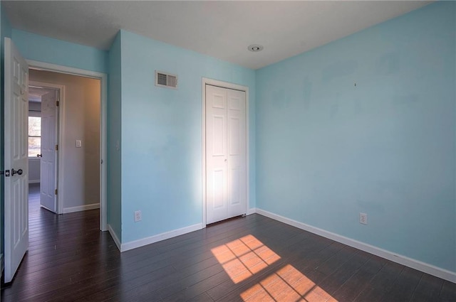 unfurnished bedroom with visible vents, baseboards, and dark wood-style flooring