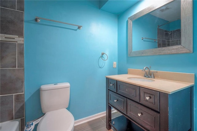 bathroom with toilet, vanity, visible vents, baseboards, and a shower