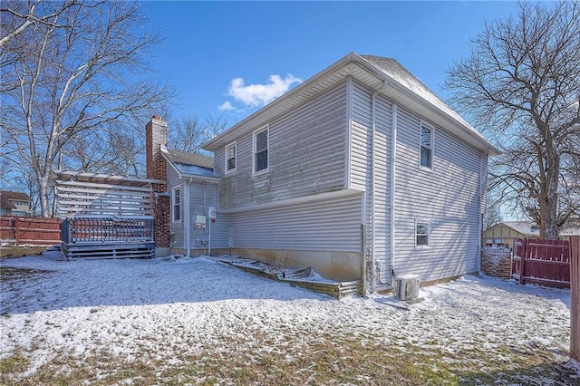 view of snowy exterior with cooling unit, fence, and a wooden deck