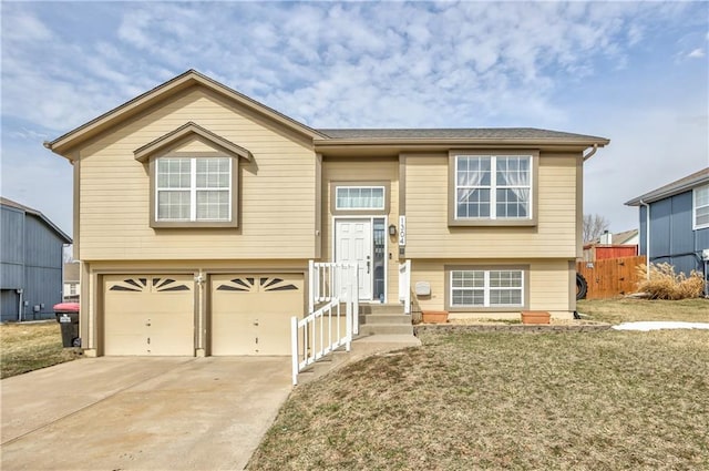 bi-level home with a front lawn, concrete driveway, fence, and an attached garage