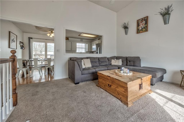 living area with a ceiling fan, carpet, and baseboards