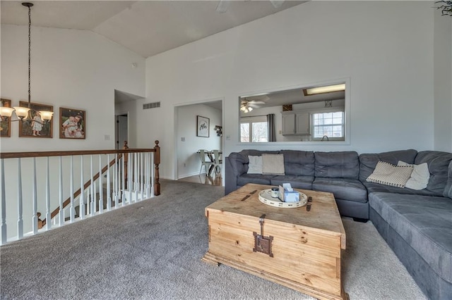 carpeted living room featuring ceiling fan with notable chandelier, high vaulted ceiling, and visible vents