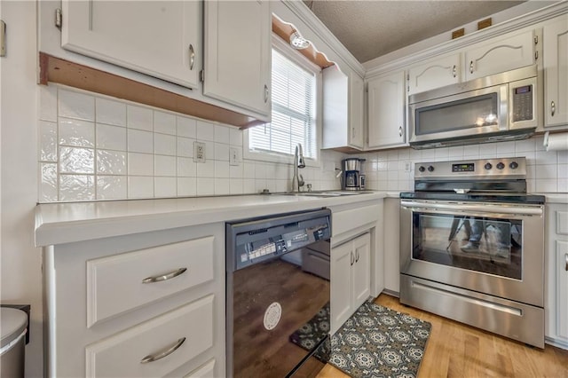 kitchen with light countertops, backsplash, light wood-style flooring, appliances with stainless steel finishes, and a sink