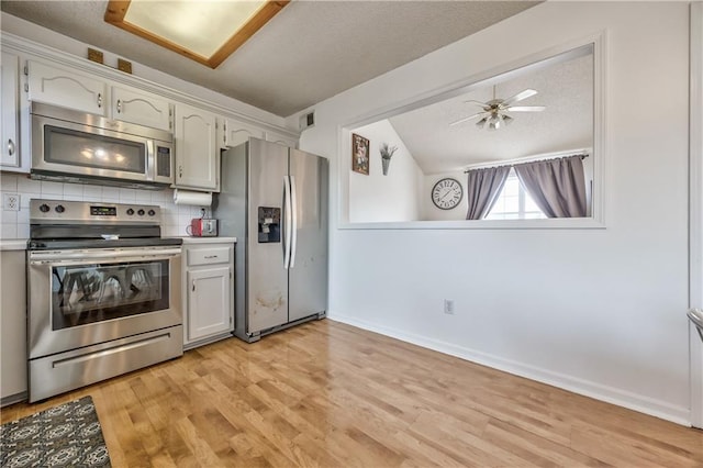 kitchen with a textured ceiling, visible vents, appliances with stainless steel finishes, decorative backsplash, and light wood finished floors