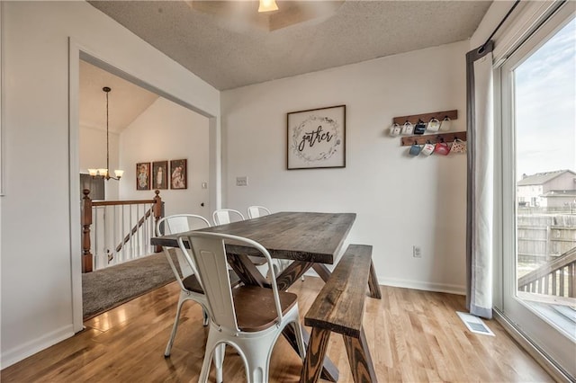 dining room with light wood-type flooring, visible vents, a chandelier, and a textured ceiling