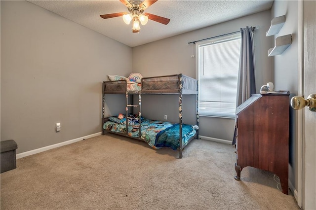 carpeted bedroom featuring a textured ceiling, a ceiling fan, and baseboards