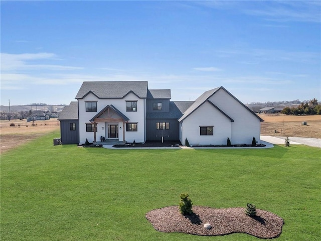 modern farmhouse style home with roof with shingles and a front yard