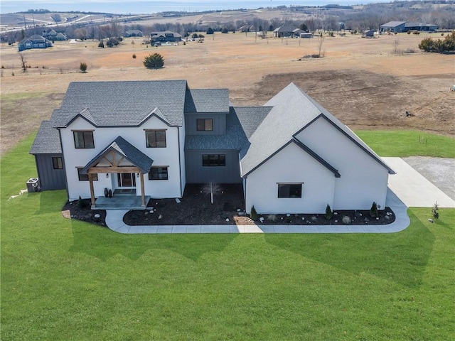 view of front of home featuring a rural view, a shingled roof, and a front lawn