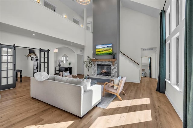 living area featuring visible vents, wood finished floors, arched walkways, and a towering ceiling