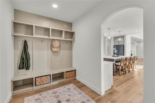 mudroom featuring recessed lighting, baseboards, arched walkways, and light wood finished floors