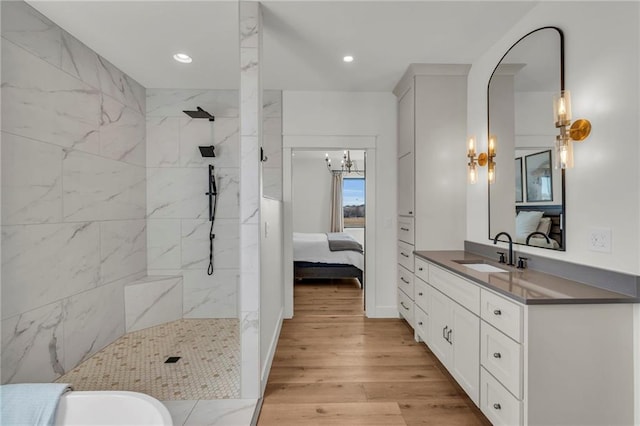 full bathroom featuring vanity, an inviting chandelier, wood finished floors, and a walk in shower