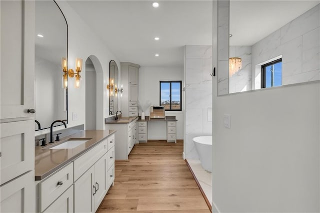 bathroom with a sink, wood finished floors, an inviting chandelier, and a wealth of natural light