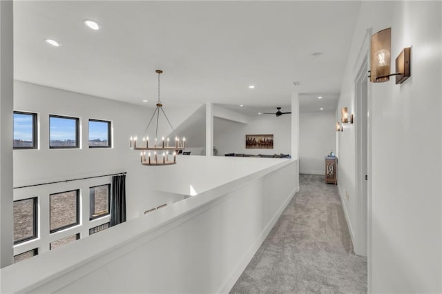 corridor with recessed lighting, light colored carpet, baseboards, and a chandelier