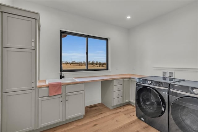 clothes washing area with recessed lighting, light wood-style floors, cabinet space, independent washer and dryer, and a sink