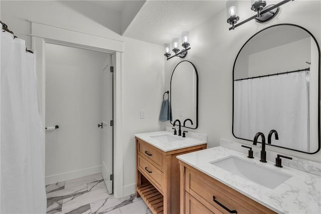 full bath featuring a sink, marble finish floor, a textured ceiling, and two vanities