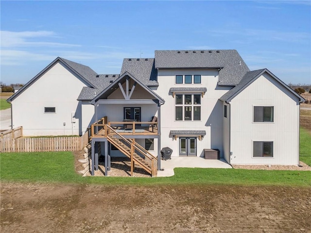 rear view of property featuring a deck, fence, a shingled roof, stairs, and a patio area